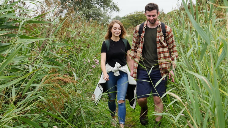 A man and woman walking between reedbeds